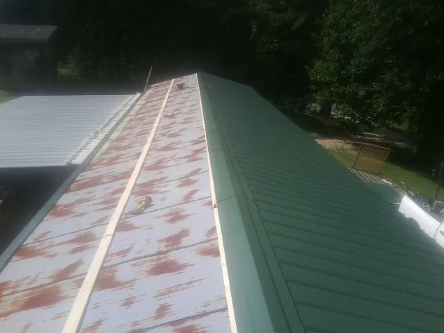 Old rusted panels beside newly installed green metal roofing — Wind Damage Roof Repair by Roofing Brothers in Woodbury Heights