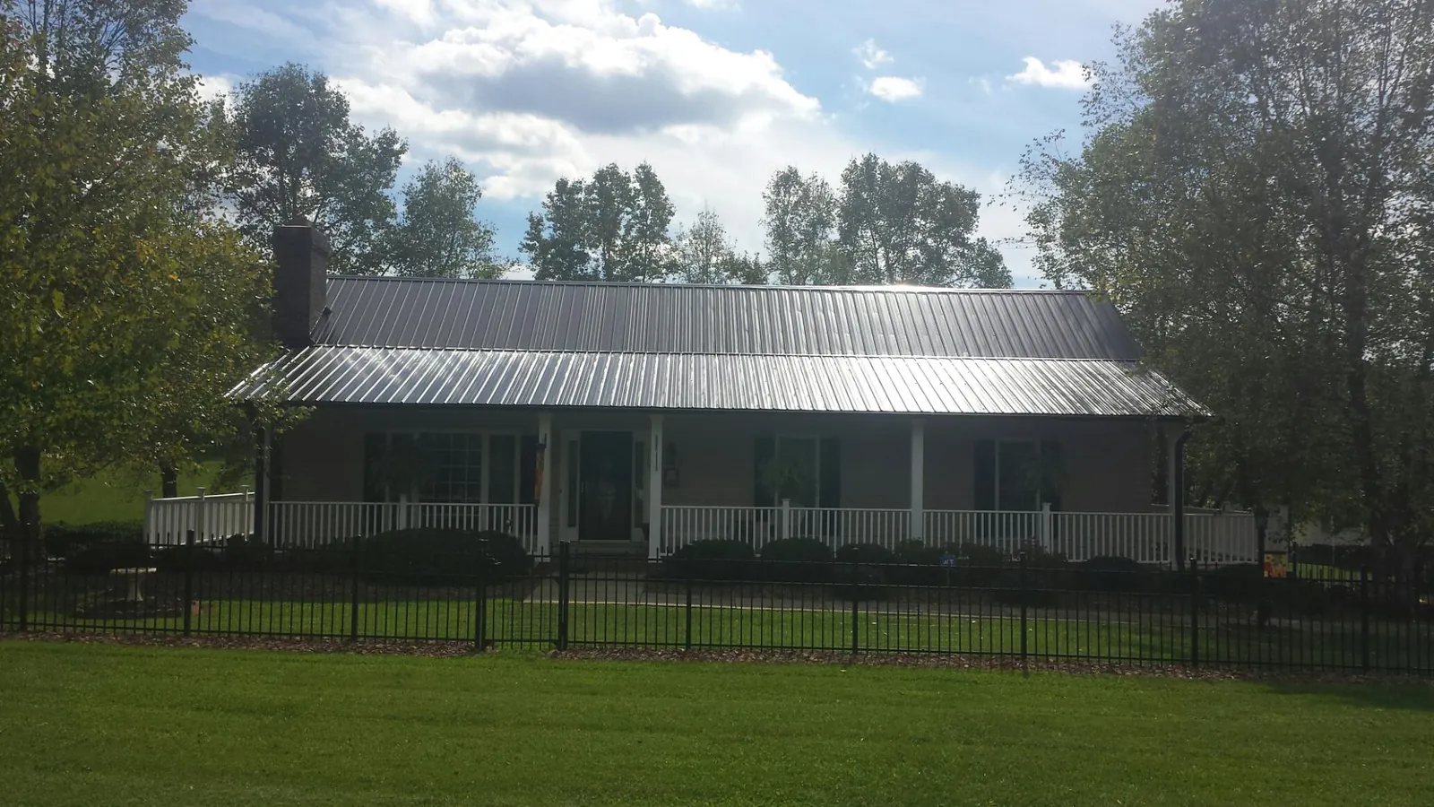 Gray metal roof on a brick ranch with a full width front porch — Gutter Guard Installation work by our crew in Woodbury Heights