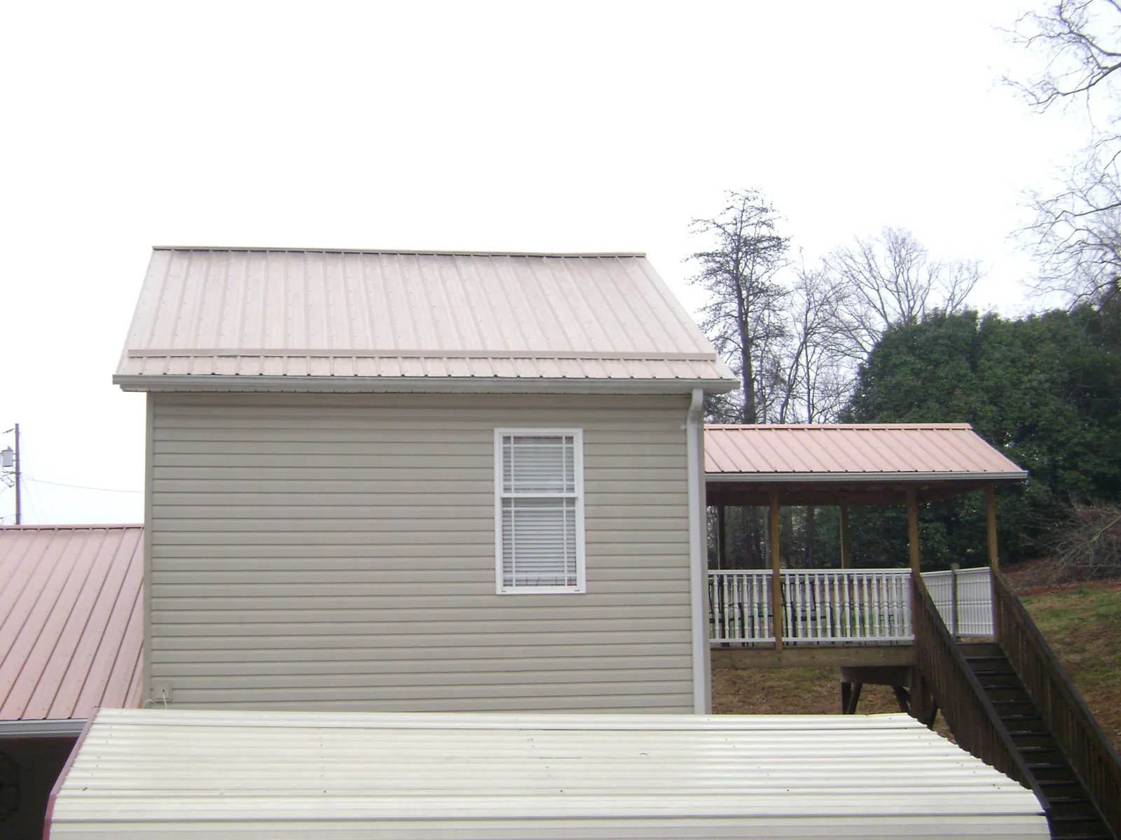 Tan metal roofs on a two story addition and attached porch, from a Roof Replacement job in Woodbury Heights
