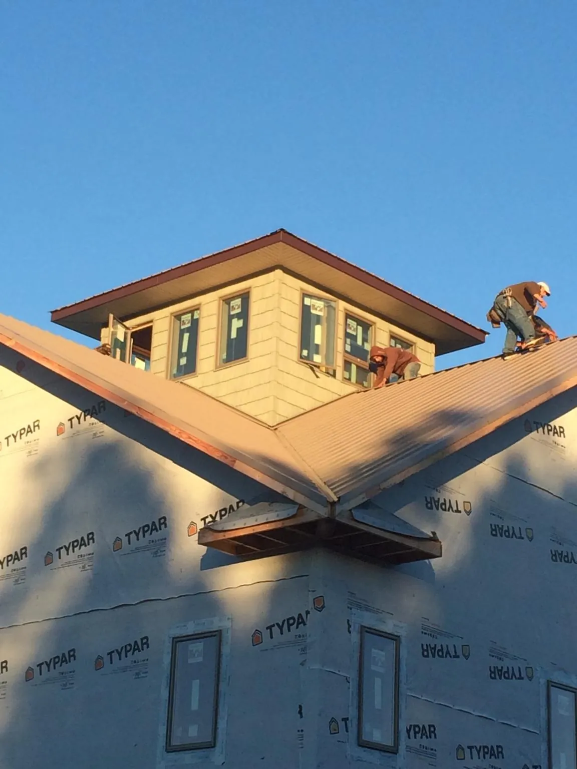 Roofers working around a rooftop cupola on a new metal roof at sunset — Roof Waterproofing in Woodbury Heights by Roofing Brothers
